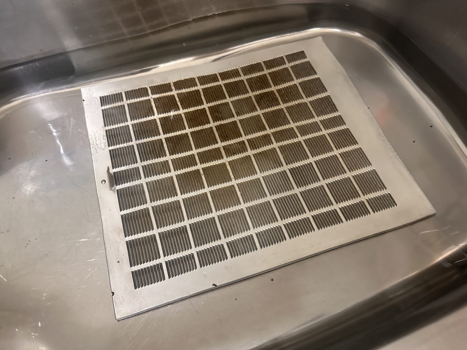 レンジフードフィルターが40℃前後のお湯に浸かっている様子