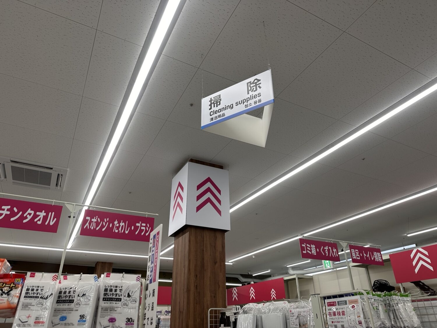 ダイソーの掃除用品コーナー。スポンジ・たわし・ブラシや風呂・トイレ用品の棚が近くに並んでいる売り場の様子
