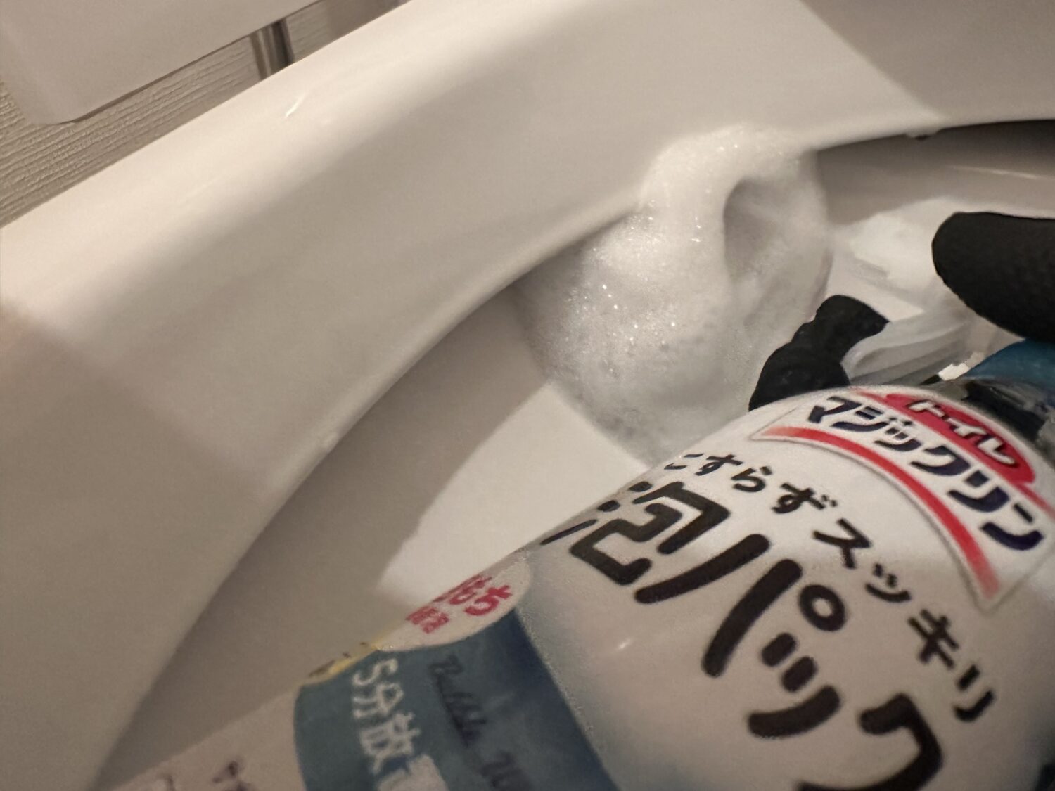 トイレマジックリン泡パックを便器のフチ裏にスプレーしている様子