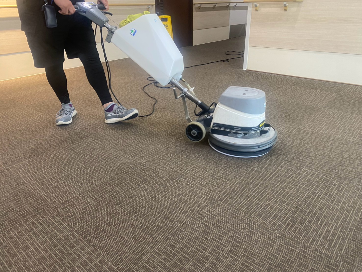 高槻市の施設でポリッシャーを使ってカーペットを洗浄している様子