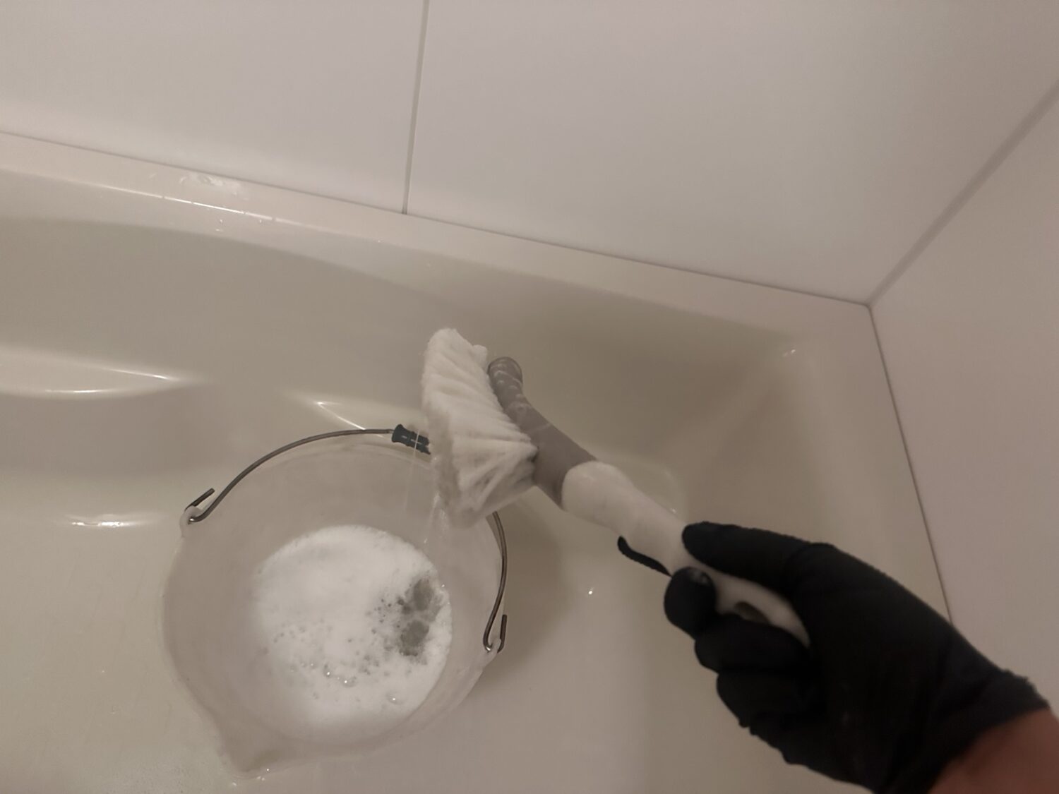 泡を含んだアズマジック浴室用ソフトブラシをバケツの上で持ち上げた状態