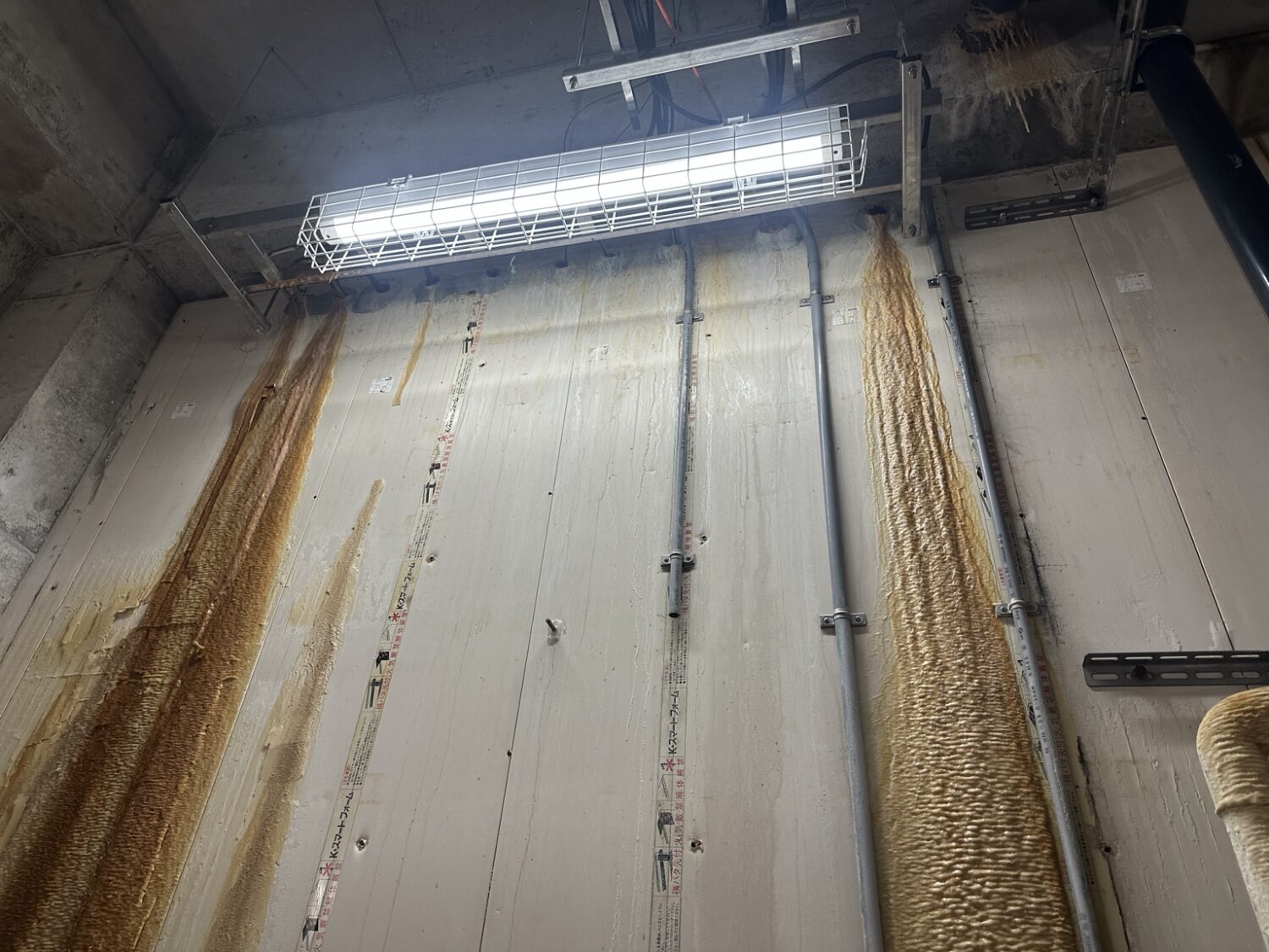 漏水後に茶色い硬質付着物が残った設備室の塩ビパネル